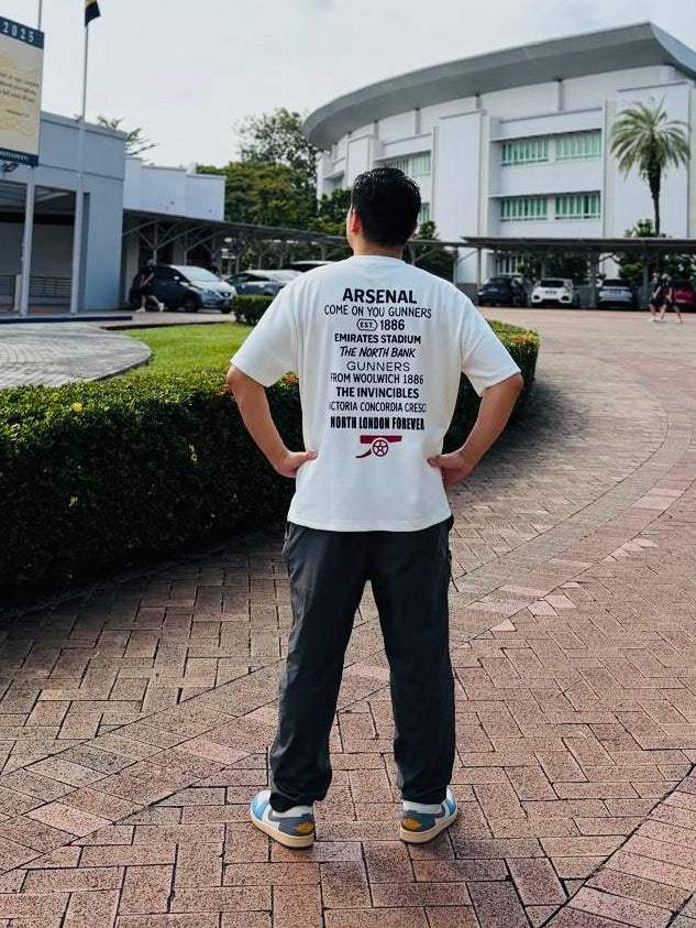 Person wearing a white t-shirt with Perfect10 words standing in front of a building with flags.