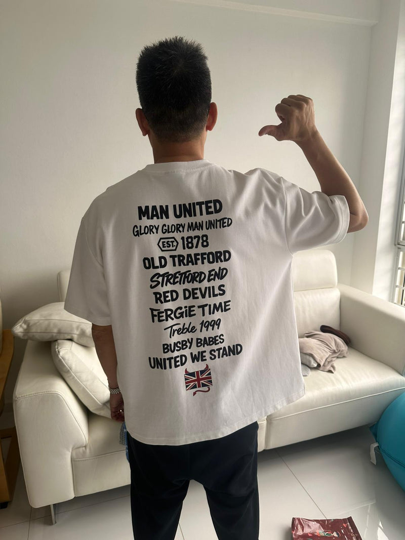 Person wearing a white t-shirt with Perfect10 graphics, standing in a living room.