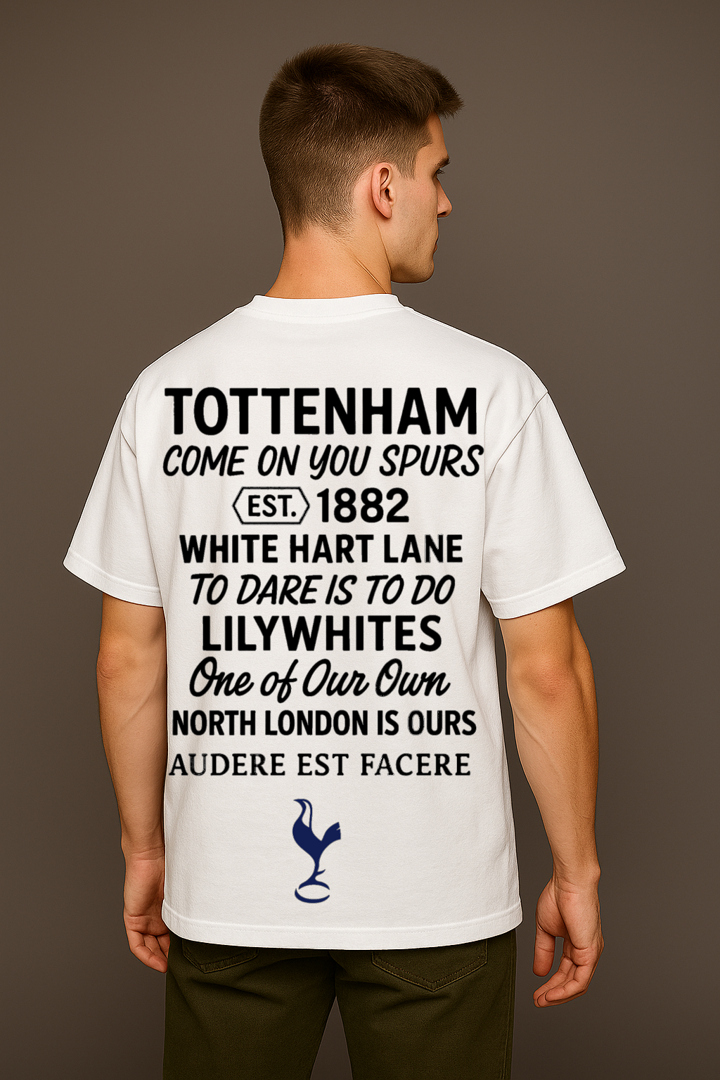 Man wearing a white t-shirt with Spurs Perfect10 and a logo on the back, standing against a brown background

